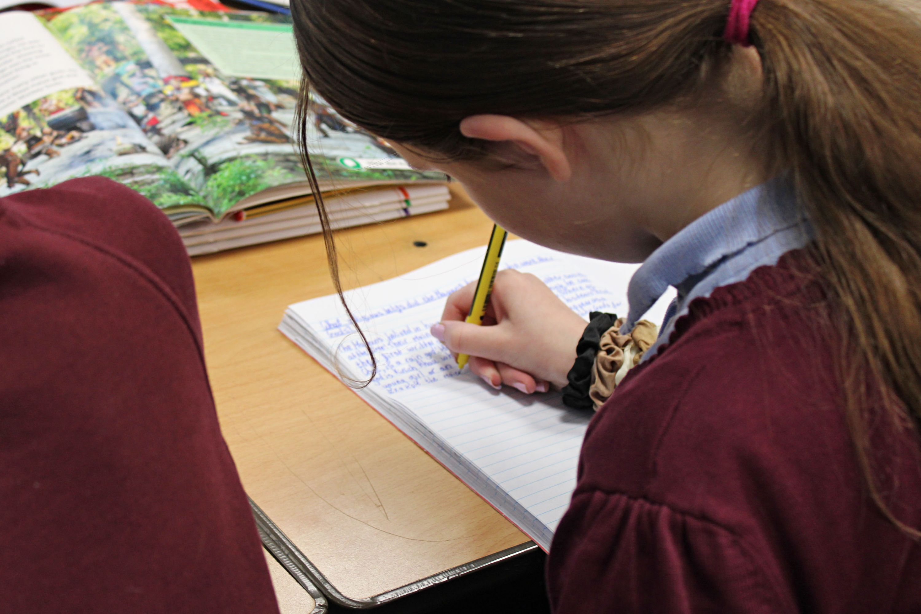 Close up of a girl writing in a workbook.